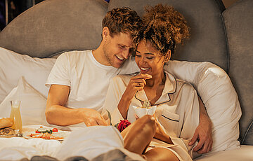 Couple enjoying breakfast in bed in a Spa Deluxe double room at the Hotel Winzer