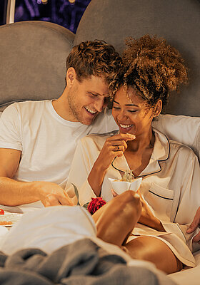Pärchen mit Frühstück im Bett im Doppelzimmer Spa Deluxe im Hotel Winzer