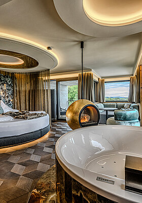 Hideaway Suite im Hotel Winzer mit privatem Whirlpool, rundem Doppelbett, freistehendem Kamin und großzügigem Wohnbereich für zwei