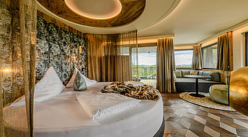 Schlafbereich der Hideaway Suite Schlafbereich der Hideaway Suite im Hotel Winzer mit rundem Doppelbett, gemütlichem Wohnbereich, Balkon und freistehendem Kamin