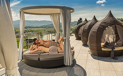 A couple are lying on comfortable sun loungers on the sun deck at the Hotel Winzer