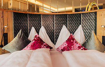 A cosy bed with pillows in the Cosy Suite at Hotel Winzer