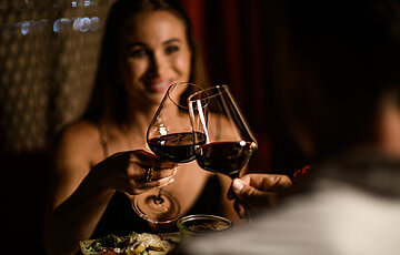 A woman with a glass of wine at the food-sharing table at the Adults Only Hotel Winzer