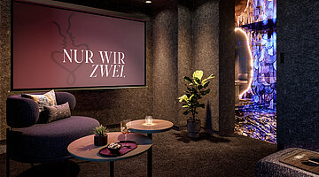 Privater Kinoraum in der Suite mit Leinwand, gemütlichem Sesseln und Blick in ein schimmerndes Badezimmer.