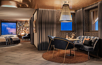 Luxuriöse Private Cinema Suite mit rundem Bett, elegantem Essbereich und kupferfarben glänzender Decke.