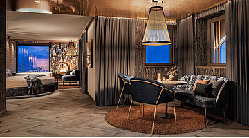 Luxuriöse Private Cinema Suite mit rundem Bett, elegantem Essbereich und kupferfarben glänzender Decke.