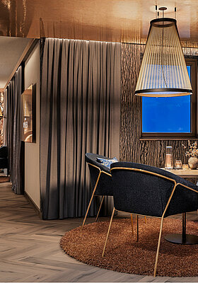 Luxuriöse Private Cinema Suite mit rundem Bett, elegantem Essbereich und kupferfarben glänzender Decke.