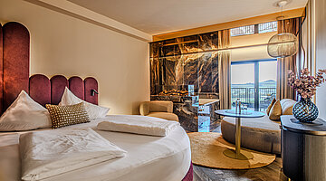Schlafbereich der Juniorsuite Kuscheltraum Deluxe Schlafbereich der Juniorsuite Kuscheltraum Deluxe im Hotel Winzer mit rundem Doppelbett, Kamin, Wohnbereich und Balkon