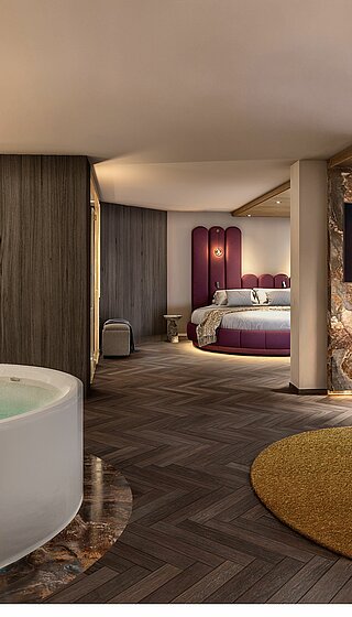 Visualisierung einer luxuriösen Hotel-Wellness-Suite. Im Vordergrund steht eine große, freistehende Whirlpool-Badewanne auf einem marmorierten Sockel. Rechts daneben befindet sich ein gemütlicher Sitzbereich mit einem runden Loungesessel, einem Beistelltisch und einem Kamin unter einem Fernseher. Im Hintergrund ist ein großer kreisförmiger Schlafbereich mit einem markanten violetten Kopfteil zu sehen. Die Suite zeichnet sich durch dunkles Fischgrätparkett, strukturierte Holz- und Marmorwände sowie warme, gedimmte Beleuchtung aus.