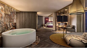 Visualisierung einer luxuriösen Hotel-Wellness-Suite. Im Vordergrund steht eine große, freistehende Whirlpool-Badewanne auf einem marmorierten Sockel. Rechts daneben befindet sich ein gemütlicher Sitzbereich mit einem runden Loungesessel, einem Beistelltisch und einem Kamin unter einem Fernseher. Im Hintergrund ist ein großer kreisförmiger Schlafbereich mit einem markanten violetten Kopfteil zu sehen. Die Suite zeichnet sich durch dunkles Fischgrätparkett, strukturierte Holz- und Marmorwände sowie warme, gedimmte Beleuchtung aus.