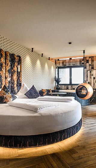 Private Cinema Suite mit Rundbett und Designkamin Private Cinema Suite im Hotel Winzer mit rundem Doppelbett, außergewöhnlichem Designkamin und stilvollem Wohnbereich für zwei