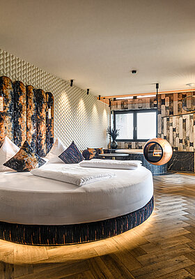Private Cinema Suite im Hotel Winzer mit rundem Doppelbett, außergewöhnlichem Designkamin und stilvollem Wohnbereich für zwei