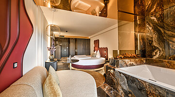 Wohnbereich der Juniorsuite Kuscheltraum Deluxe Gemütlicher Wohnbereich der Juniorsuite Kuscheltraum Deluxe im Hotel Winzer mit Sitzecke, Kamin, Balkon und Blick in die Landschaft