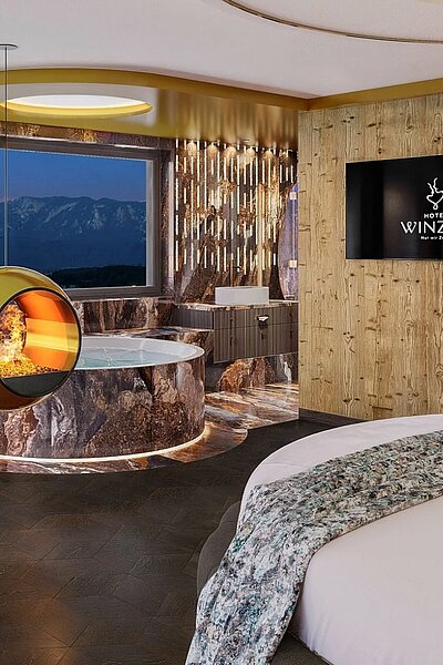 Tadaaa – wir dürfen vorstellen: Unsere Hideaway Suite. 43 m² voller Ruhe und Zweisamkeit. Rundbett. Panorama-Daybed. Runder Whirlpool für zwei. Kamin mit sanftem Effektfeuer.
